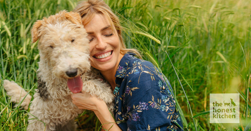 A woman hugging a medium-sized dog in a field